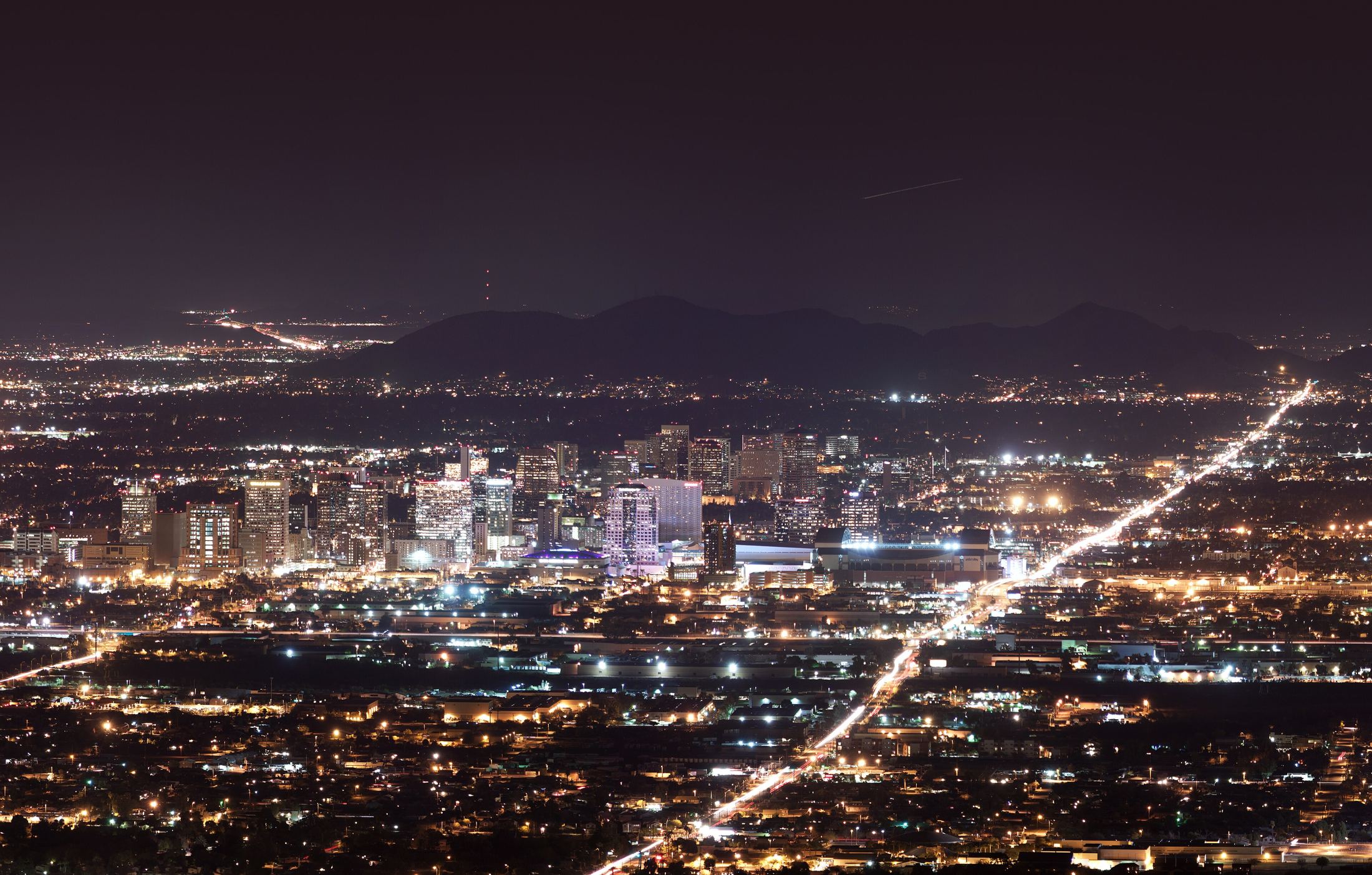 Downtown Phoenix at night, the city lights reaching to the mountains