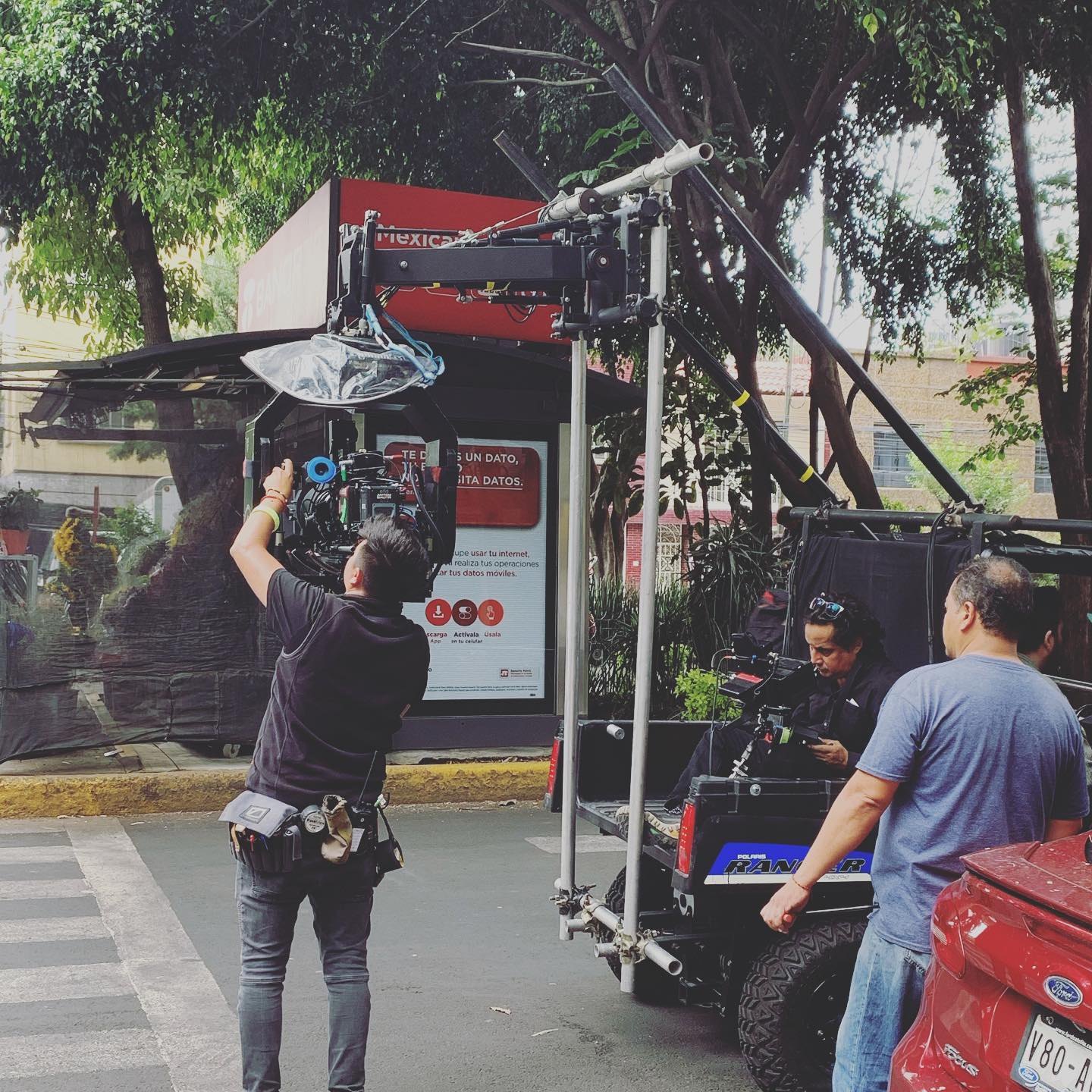 A film crew rigging a camera crane on a Mexico City street corner