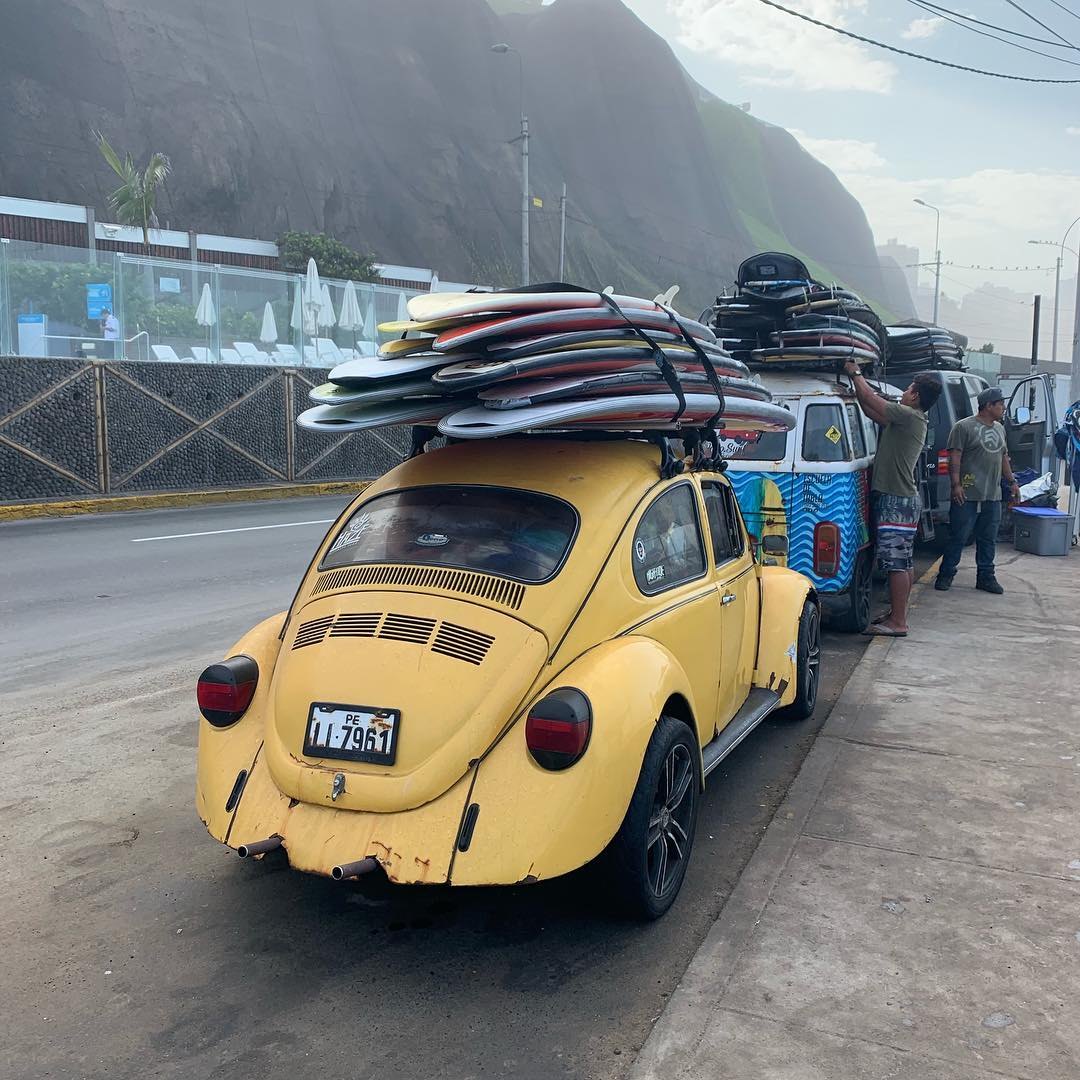 Surfboards stacked on a yellow Volkswagen Beetle on the Costa Verde, under the Miraflores cliffs