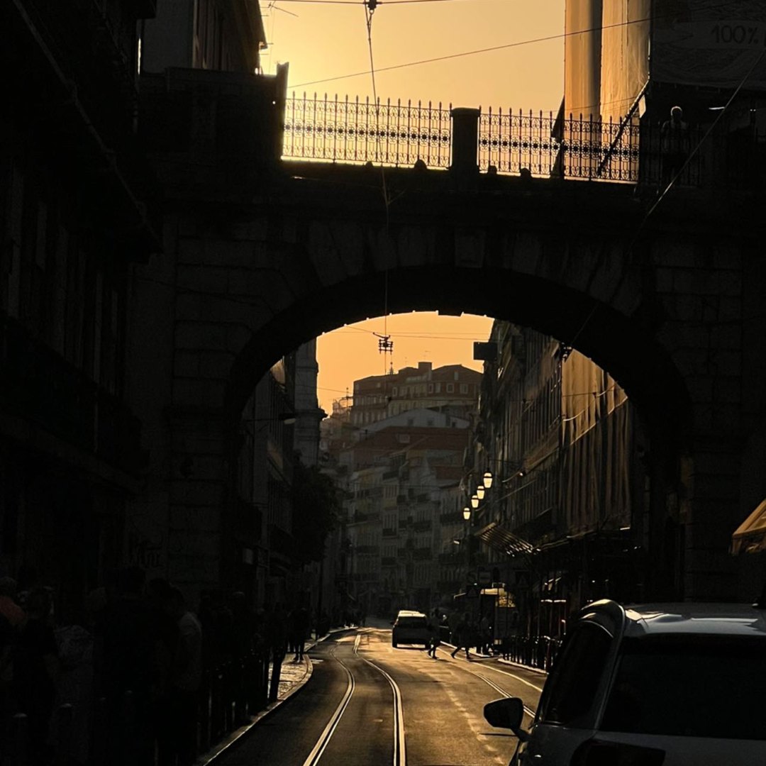 An arch over tram lines in Bairro Alto, silhouetted at sunset
